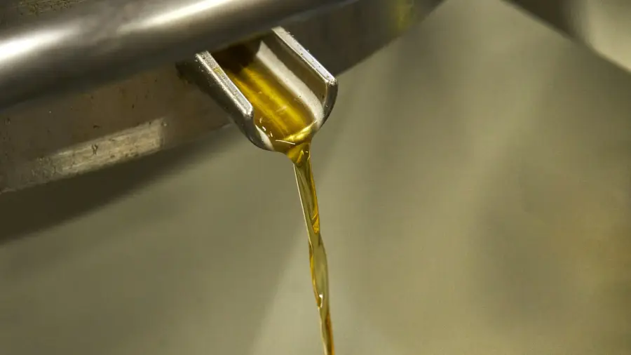 Aceite dorado vertiéndose desde un pico metálico